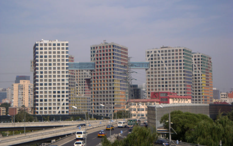 Colorful grid-window office towers beside a busy urban expressway in Beijing.