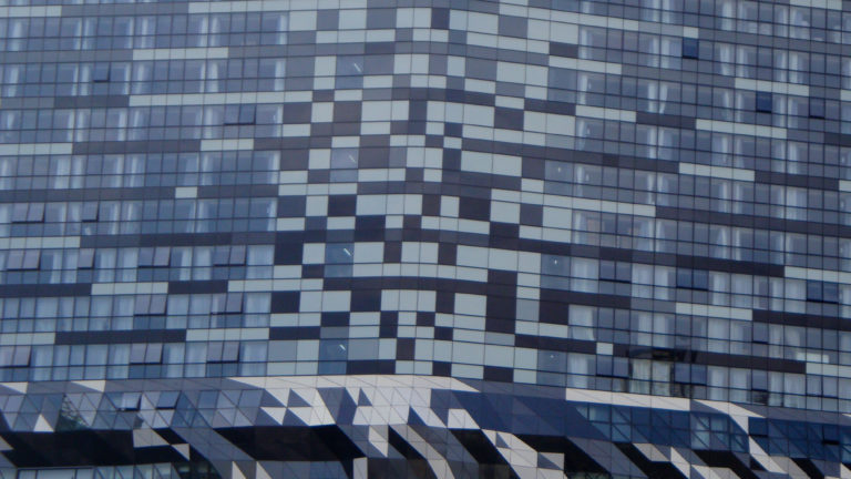 Close view of a pixel-like checkerboard glass facade on a contemporary high-rise building in Beijing.