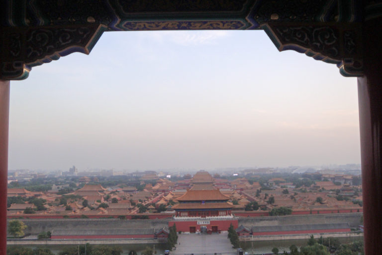 Elevated panorama of the Forbidden City from Jingshan Park, showing palace roofs aligned along a central north–south axis.