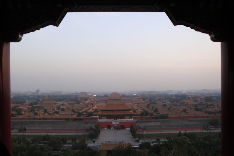 Elevated panoramic view of the Forbidden City from Jingshan Park, showing palace roofs aligned along the central north–south axis.