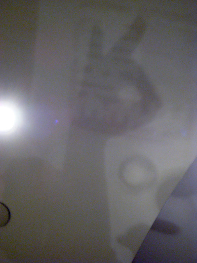 Abstract, heavily blurred interior scene with bright light glare and indistinct gray shapes, subject not identifiable.