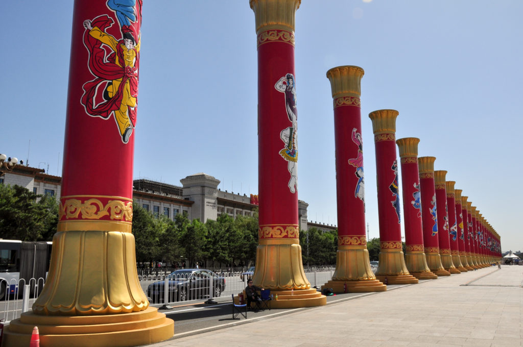Rows of temporary red-and-gold ceremonial columns in linear perspective across Tiananmen Square.