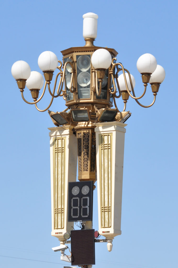 Ornate multi-lamp streetlamp with curved arms and clock-like medallions in Tiananmen Square.