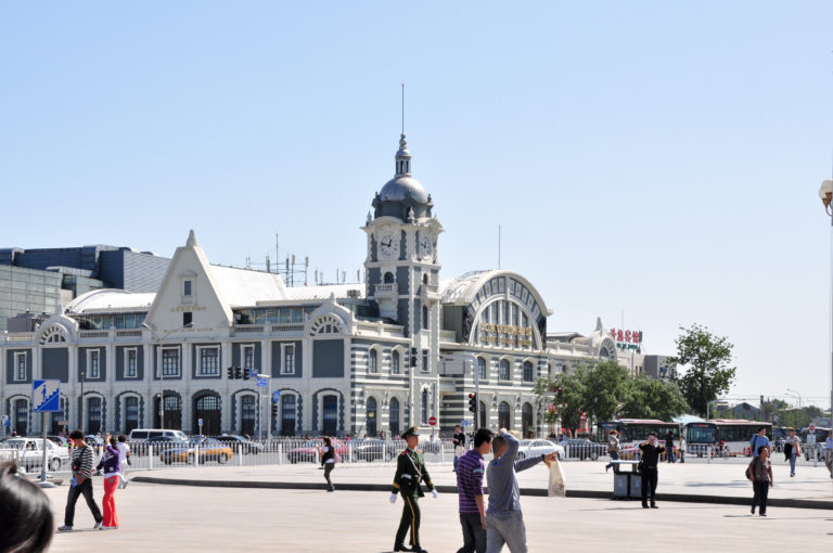 Beijing Railway Museum in the former Zhengyangmen East Railway Station, with a European-influenced facade, clock tower, and pedestrians crossing a broad paved foreground.