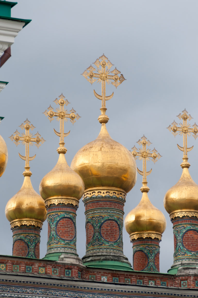 Close view of broad gilded cupolas, ornate Orthodox crosses, and richly patterned drums on the Terem Palace churches.