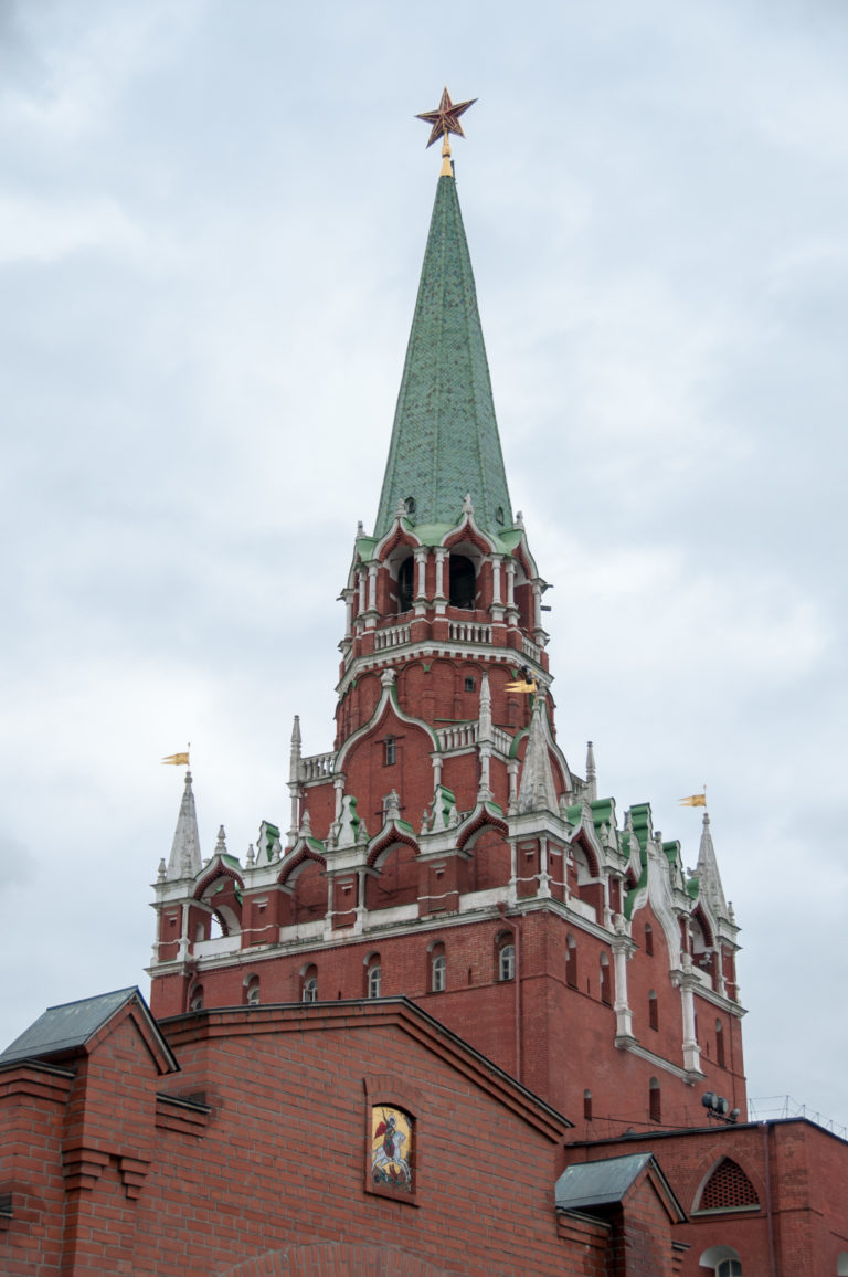 Red-brick Kremlin tower with white decorative accents, steep green roof, and red star above the wall.