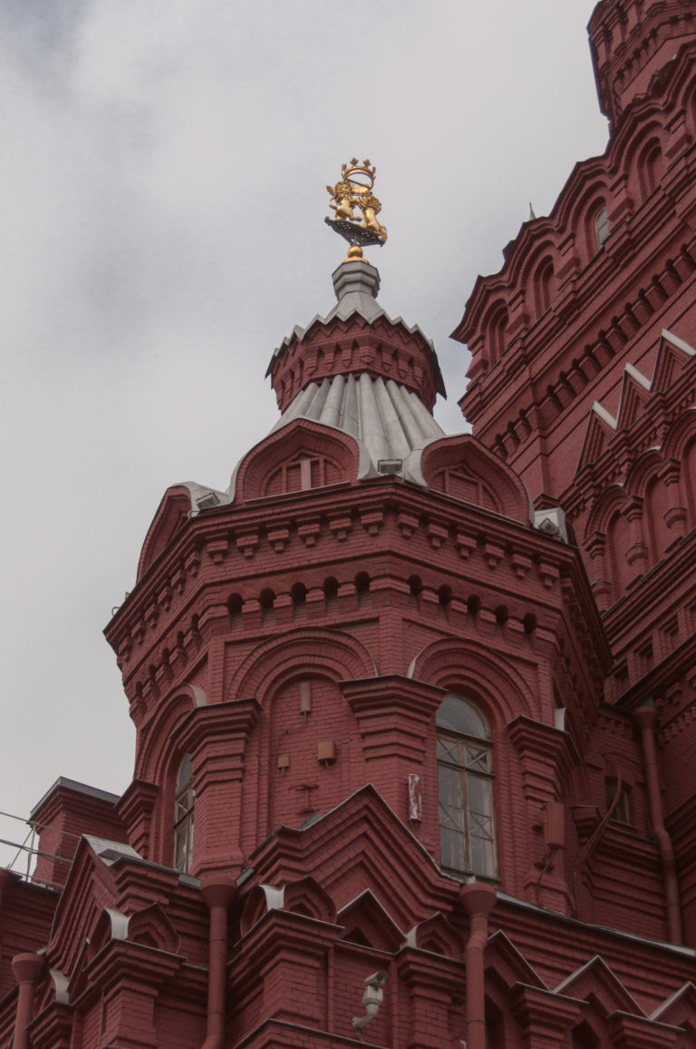 Low-angle detail of Kazan Cathedral showing red walls, layered white trim, curved gables, and a gilded roof finial.