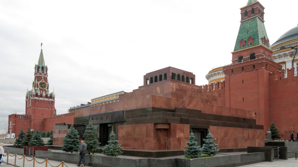 Lenin Mausoleum on Red Square with its stepped red-and-dark stone form and Kremlin towers rising behind.