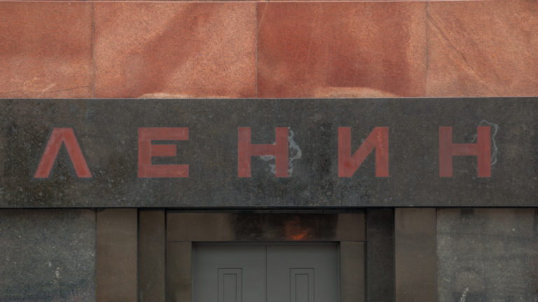 Cyrillic letters spelling Lenin in red across dark polished stone above the mausoleum entrance.