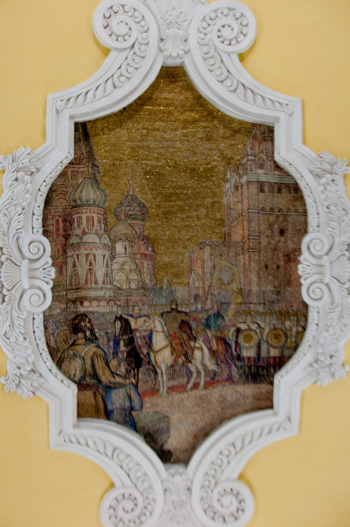 Gold-toned ceiling mosaic with riders and a procession before onion-domed buildings, framed by white plaster scrollwork.