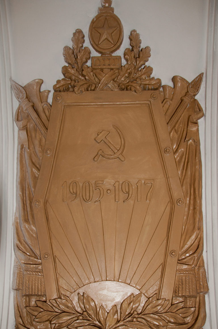Bronze-toned 1905–1917 commemorative panel with hammer and sickle, star, banners, weapons, and radiating lines.