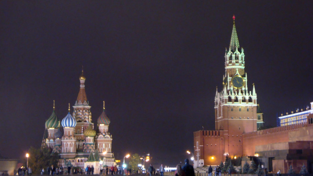 Saint Basil’s Cathedral and Spasskaya Tower illuminated at night with visitors gathered across Red Square.