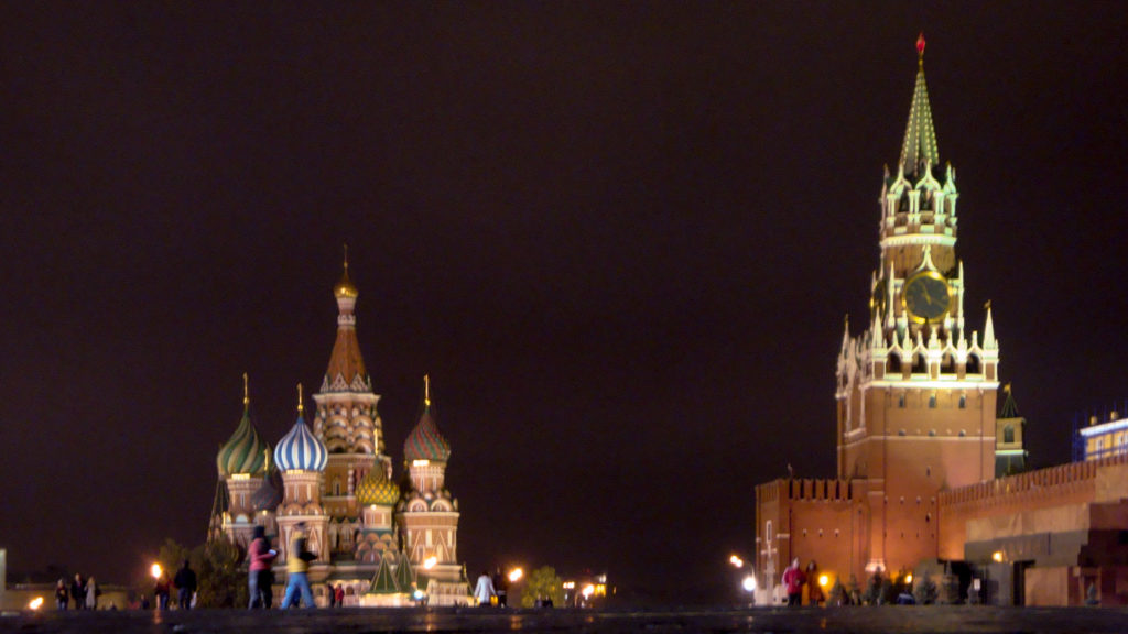Saint Basil’s Cathedral at left and illuminated Spasskaya Tower at right across Red Square at night.