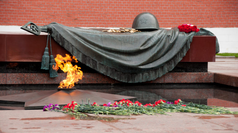 Eternal Flame burning before the bronze helmet and draped banner memorial at the Tomb of the Unknown Soldier by the Kremlin wall.