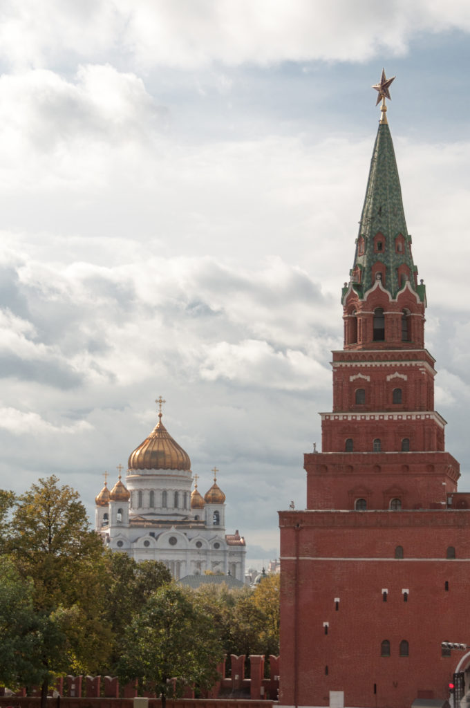 Red-brick Kremlin tower with green star-topped roof at right and the white, gold-domed Cathedral of Christ the Saviour in the distance.