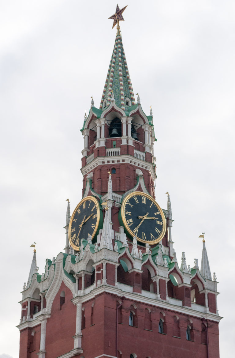 Close view of Spasskaya Tower’s black-and-gold clocks beneath a green spire topped by a red star.