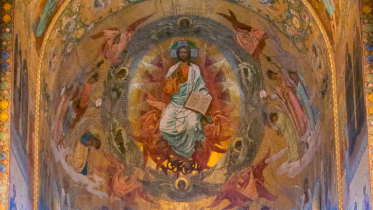 Enthroned Christ holding an open book within a luminous oval, surrounded by angels in a curved mosaic.