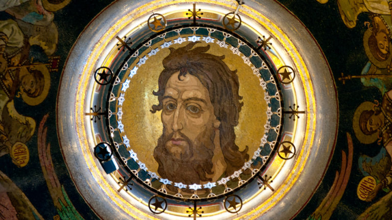Circular gold-ground mosaic of Christ’s face surrounded by a metal lighting ring with small cross-shaped fittings.