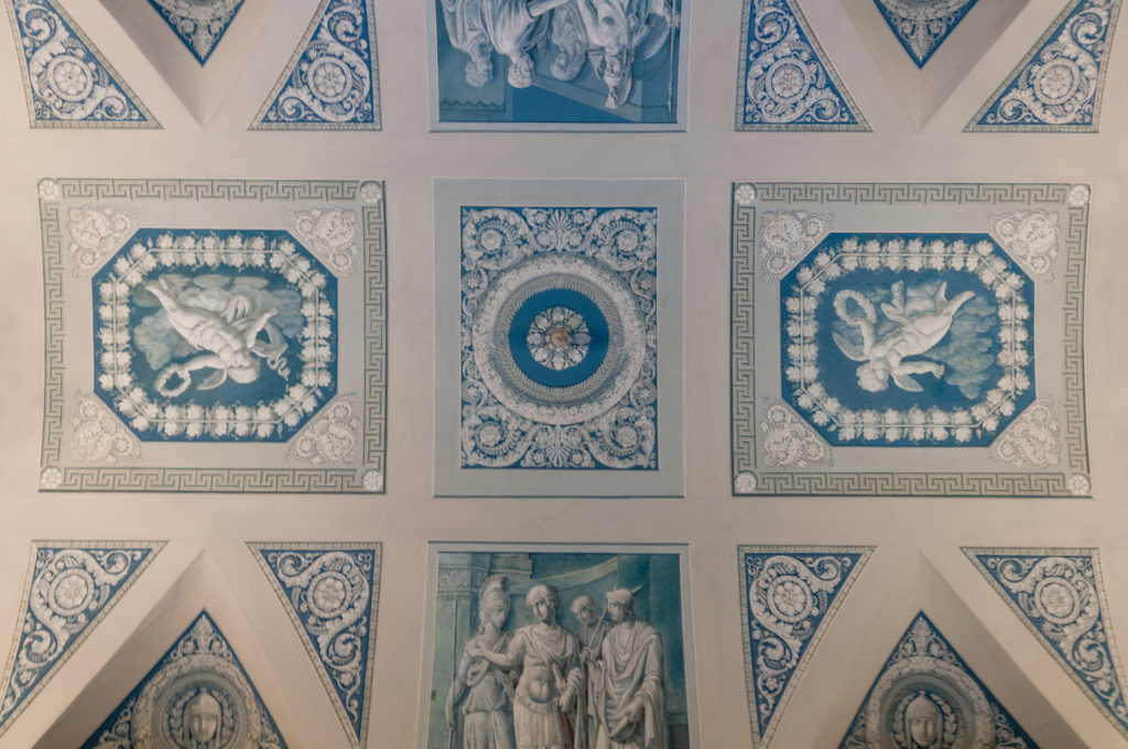 Blue-and-white coffered ceiling filled with figural reliefs, rosettes, borders, and geometric decorative panels.