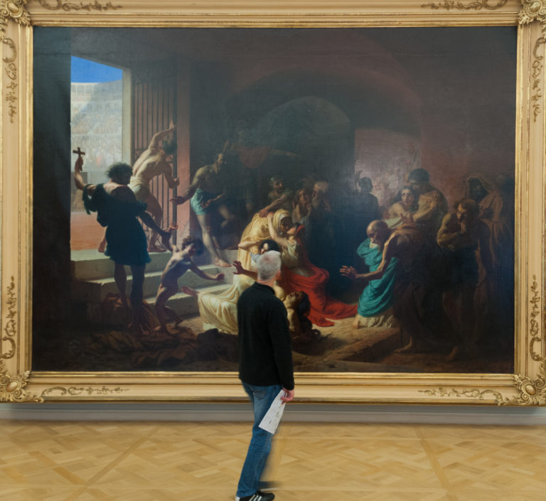 Museum visitor faces a huge framed historical painting filled with figures gathered around a brightly lit central scene.