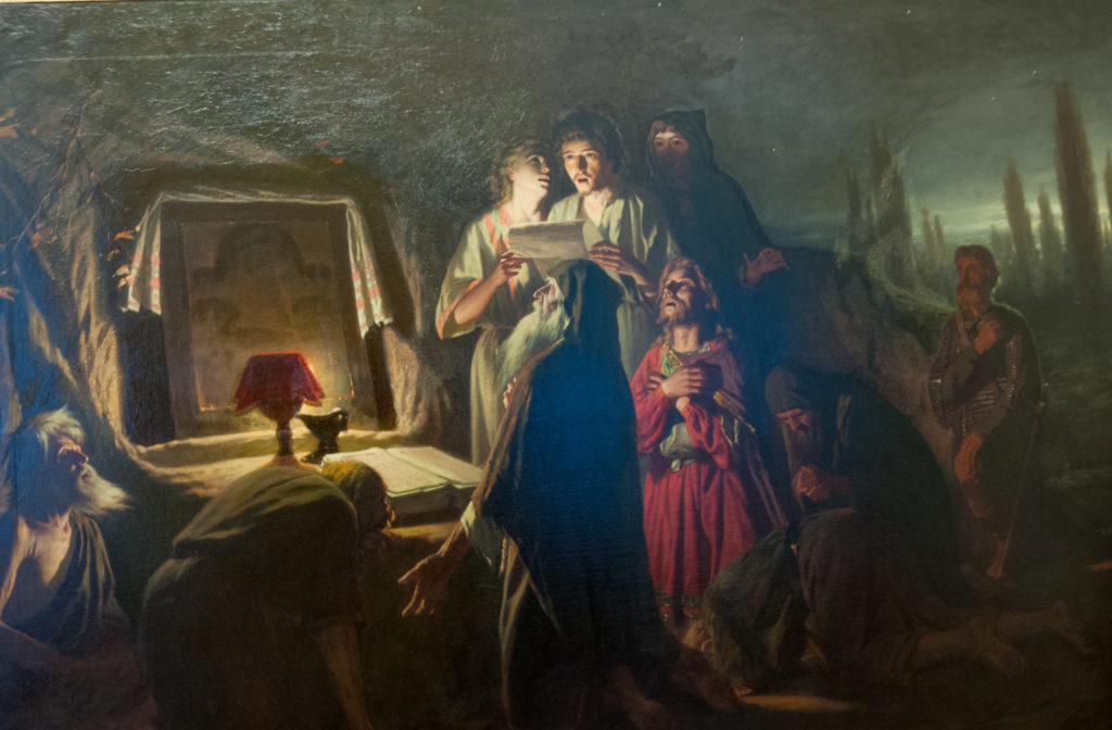 Dark historical painting with a brightly lit woman raising her hands beside a lamp, surrounded by reacting figures.