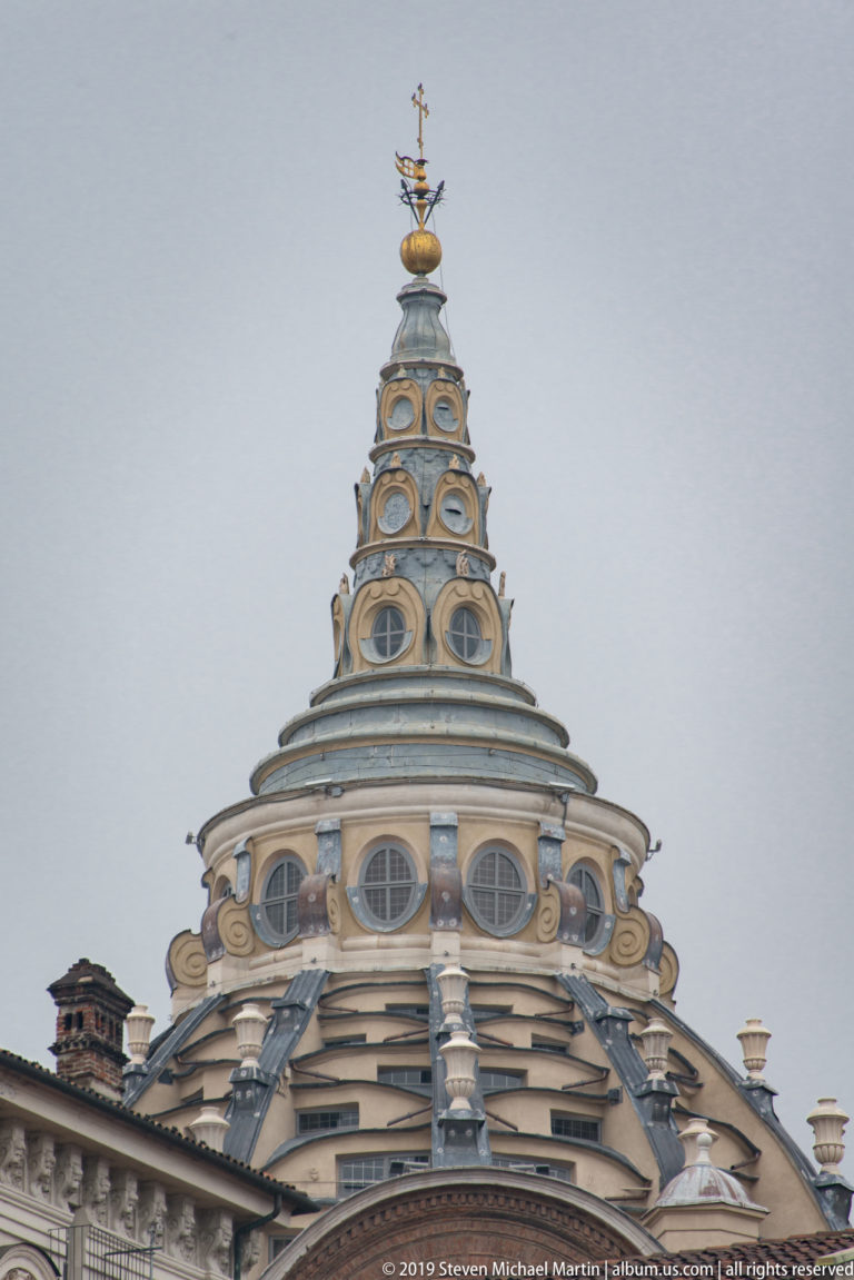Upper dome and spire of the Mole Antonelliana, with stacked oval windows and layered pale roof structure.