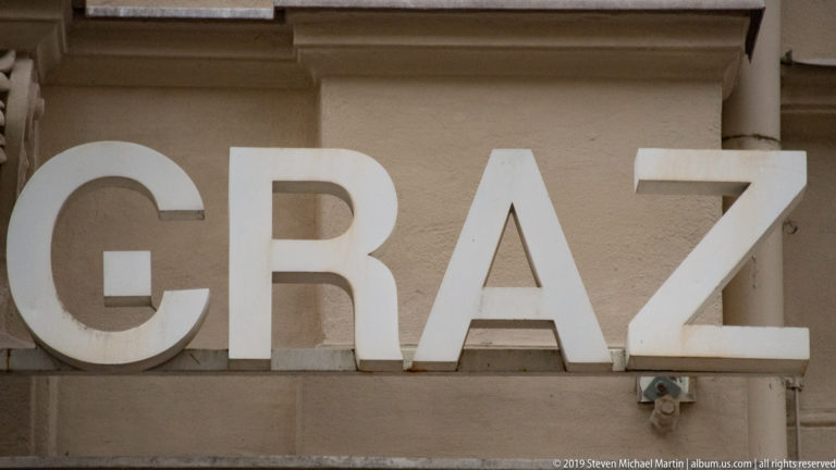 Large white three-dimensional letters spelling GRAZ mounted on a beige exterior wall.