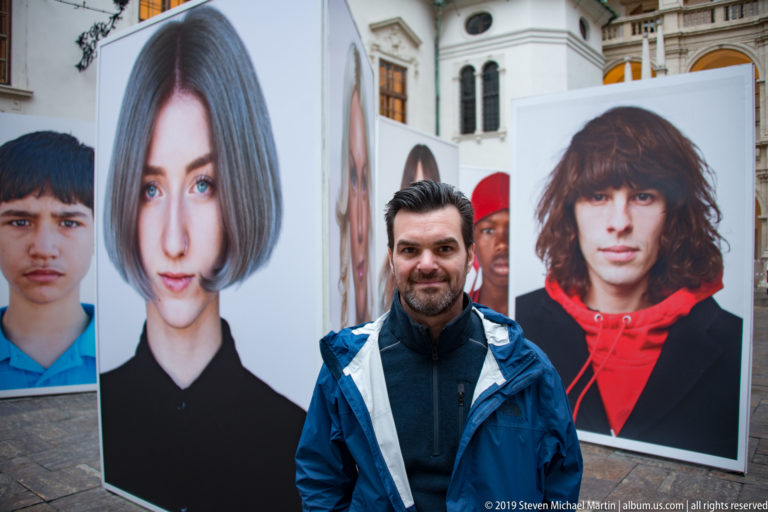 Man standing among tall freestanding photographic portrait panels in a Renaissance courtyard in Graz.