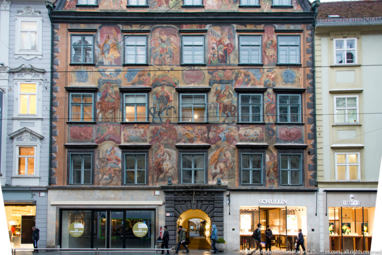 Fresco-covered façade of the Gemaltes Haus on Herrengasse, with rows of windows and shops at street level.