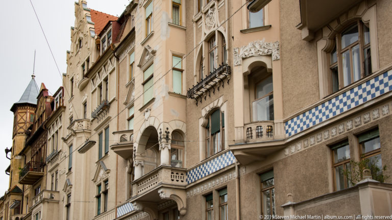 Ornamented multi-story facades with balconies, carved window surrounds, and a blue-and-white checkerboard frieze.