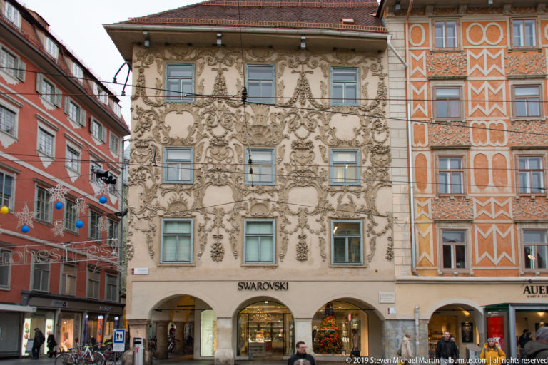Richly decorated stucco façade of Luegghaus above arched ground-floor shops on Graz Hauptplatz.