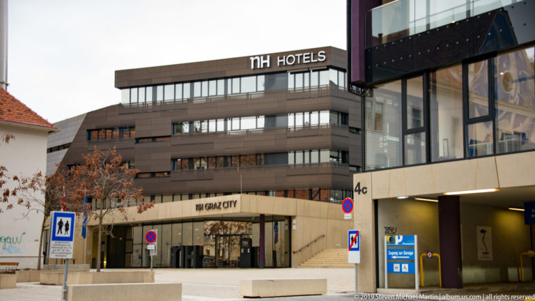 Modern NH Hotels building with horizontal windows and retail entrance in Graz.