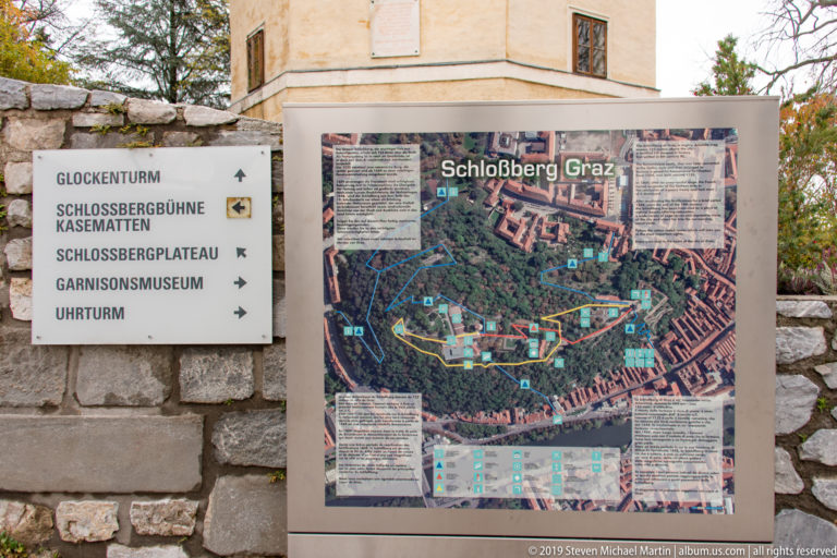 Schloßberg Graz map beside directional signs for Glockenturm, Kasematten, plateau, museum, Uhrturm, and other attractions.