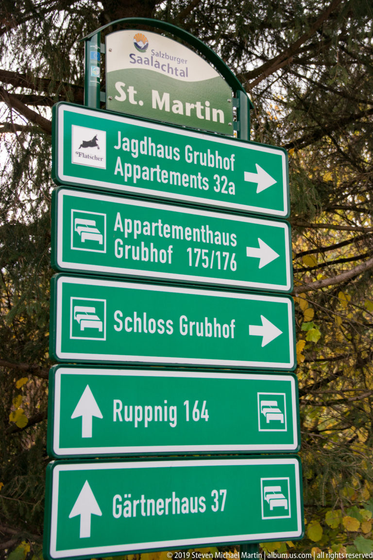 Green St. Martin directional signs pointing to Grubhof properties, Rupping, and Gärtnerhaus among trees.