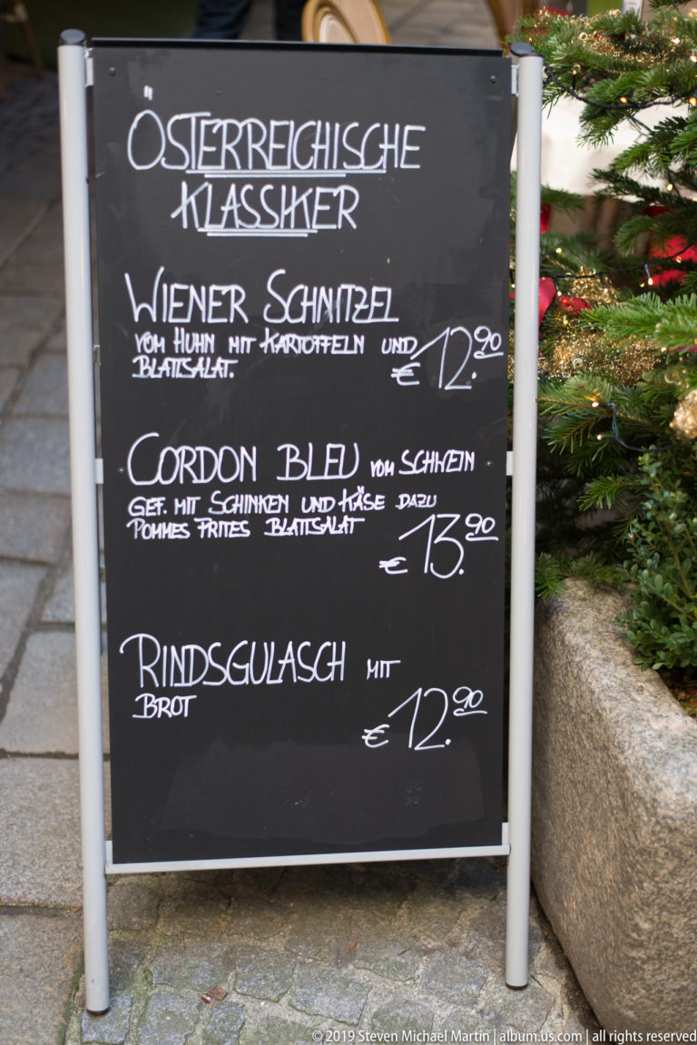 Black chalkboard menu listing Wiener Schnitzel, Cordon Bleu, and Rindsgulasch with prices in handwritten German.