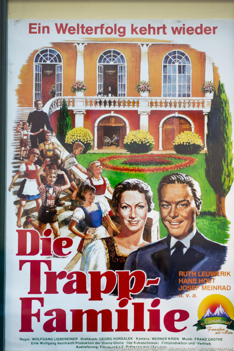 Vintage German-language Die Trapp-Familie poster with illustrated cast portraits, large red title lettering, and a stately house.