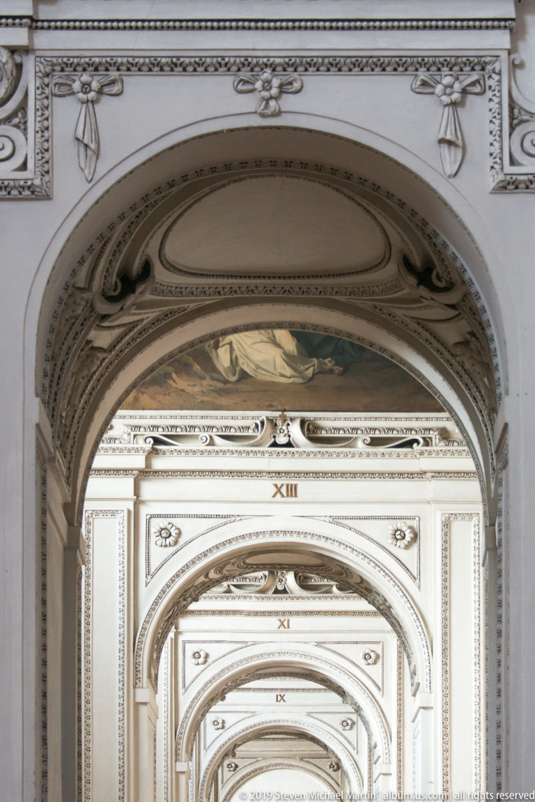 Repeated pale ceiling arches marked with Roman numerals receding through the cathedral interior.