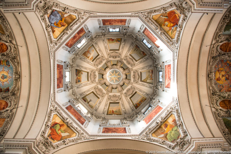 Centered upward view into the octagonal crossing dome with painted panels, windows, ribs, and corner frescoes.