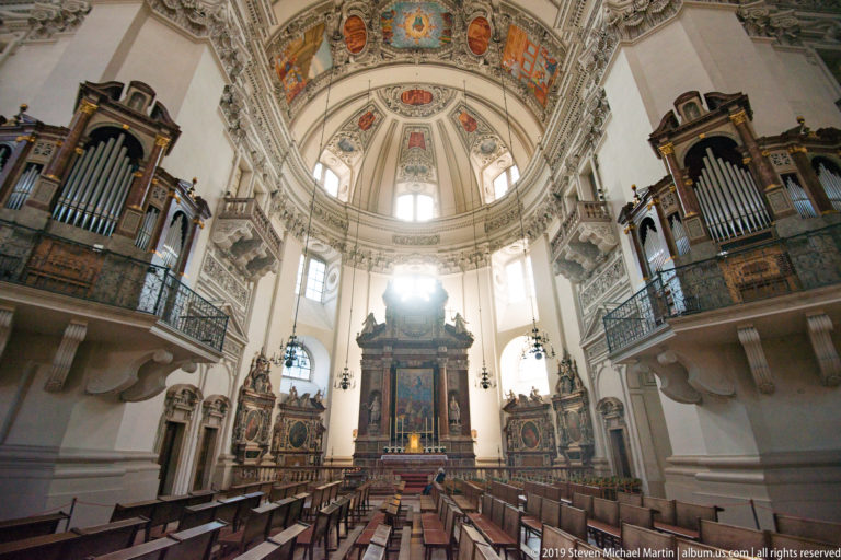 Salzburg Cathedral sanctuary with high altar centered beneath the dome and large pipe organs on galleries to both sides.