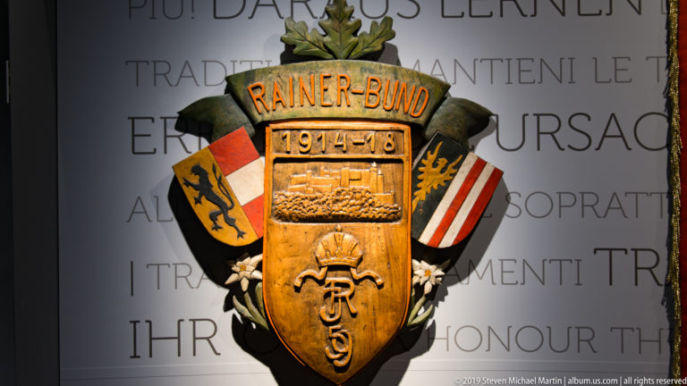 Carved Rainer-Bund 1914–18 emblem with central shield, heraldic panels, crown, and military ornament.