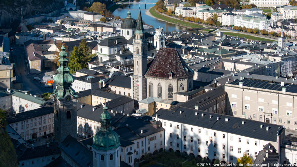 Elevated view over Salzburg Cathedral, surrounding historic rooftops, church towers, and the Salzach River.