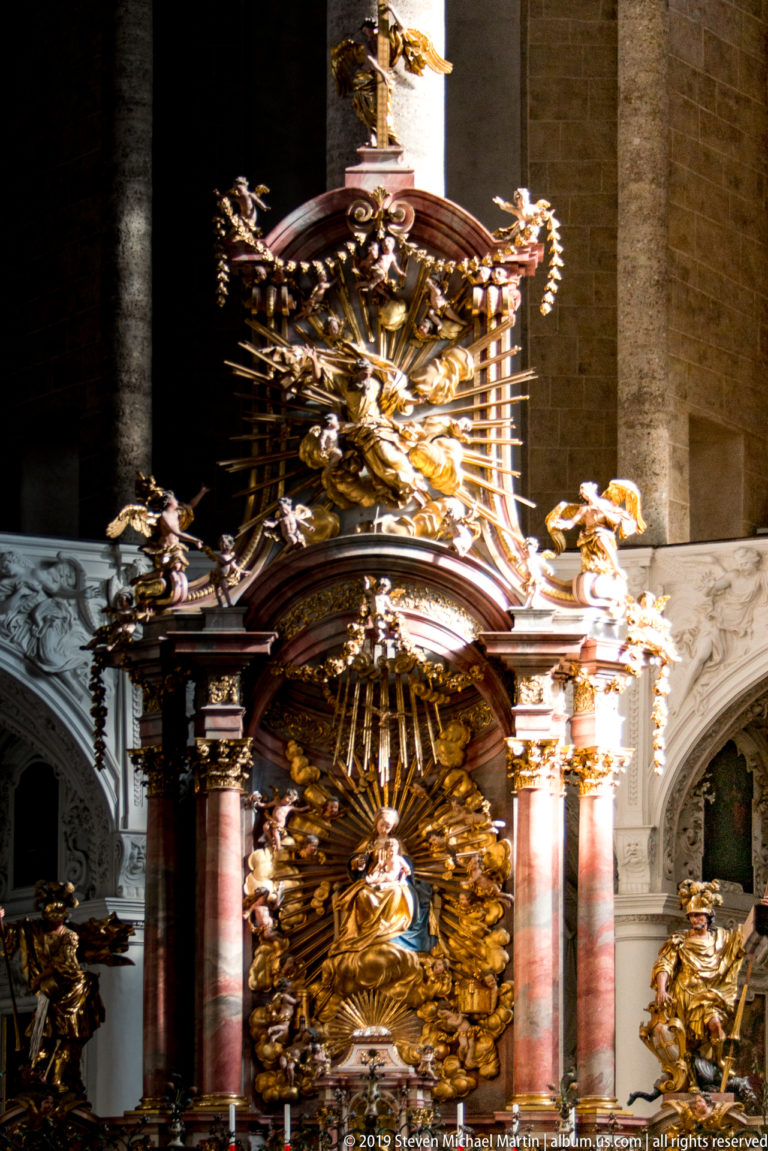 Close view of the high altar’s rose-colored columns, gilded ornament, sculpted figures, and projecting Baroque canopy.