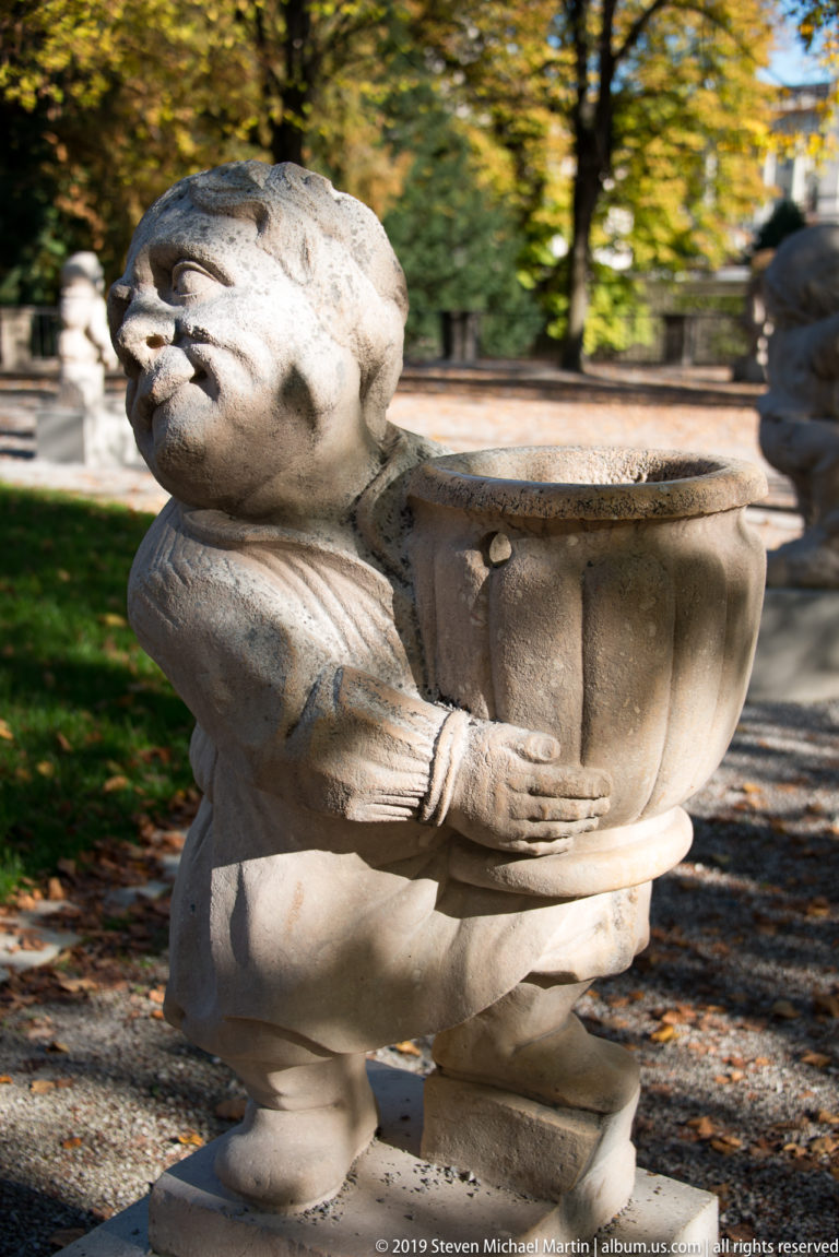 Stone dwarf supporting a large ribbed basin with both hands in the Mirabell Dwarf Garden.