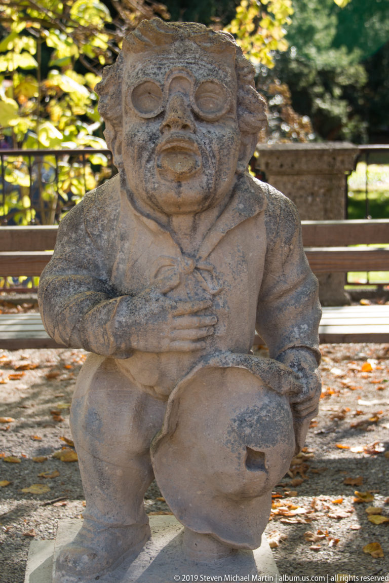 Crouching stone dwarf with a round mask-like face covering marked by large circular eyes and mouth.