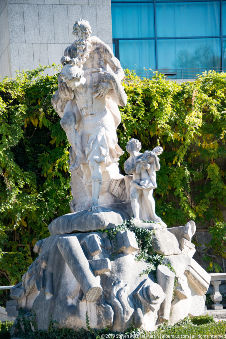 Large pale stone fountain sculpture with several figures and a broad basin in Mirabell Gardens.