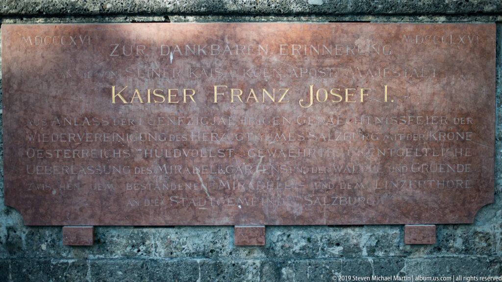 Reddish stone memorial plaque with gilded German inscription KAISER FRANZ JOSEF I set into a darker wall.