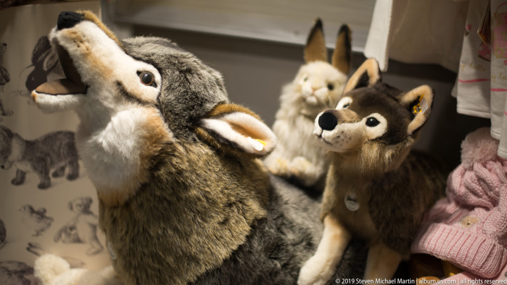 Realistic plush rabbits and a fox-like toy grouped closely together in a warmly lit shop display.