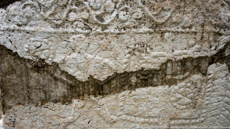 Close view of weathered limestone carving with a recessed horizontal band and faint geometric relief.