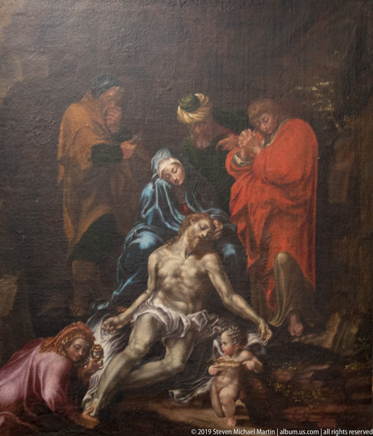 Dark religious painting with the dead Christ supported by mourners, a veiled woman in blue, and a small cherub.