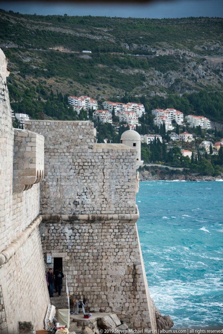 Massive stone fortification rising directly above turquoise Adriatic water.